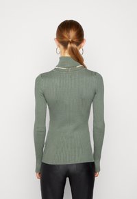 Green ribbed turtleneck sweater with long sleeves and a fitted shape, featuring a textured fabric and a high collar.