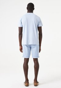 Lichtblauwe katoenen t-shirt en bijpassende shorts, beide met een comfortabele pasvorm. De shorts hebben opgerolde boorden en een eenvoudig ontwerp zonder patronen.