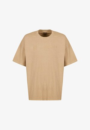 Beige pamut póló laza fazonnal, kerek nyakkal és rövid ujjakkal. Elülső részén finom hímzett logóval rendelkezik világosabb fonallal.