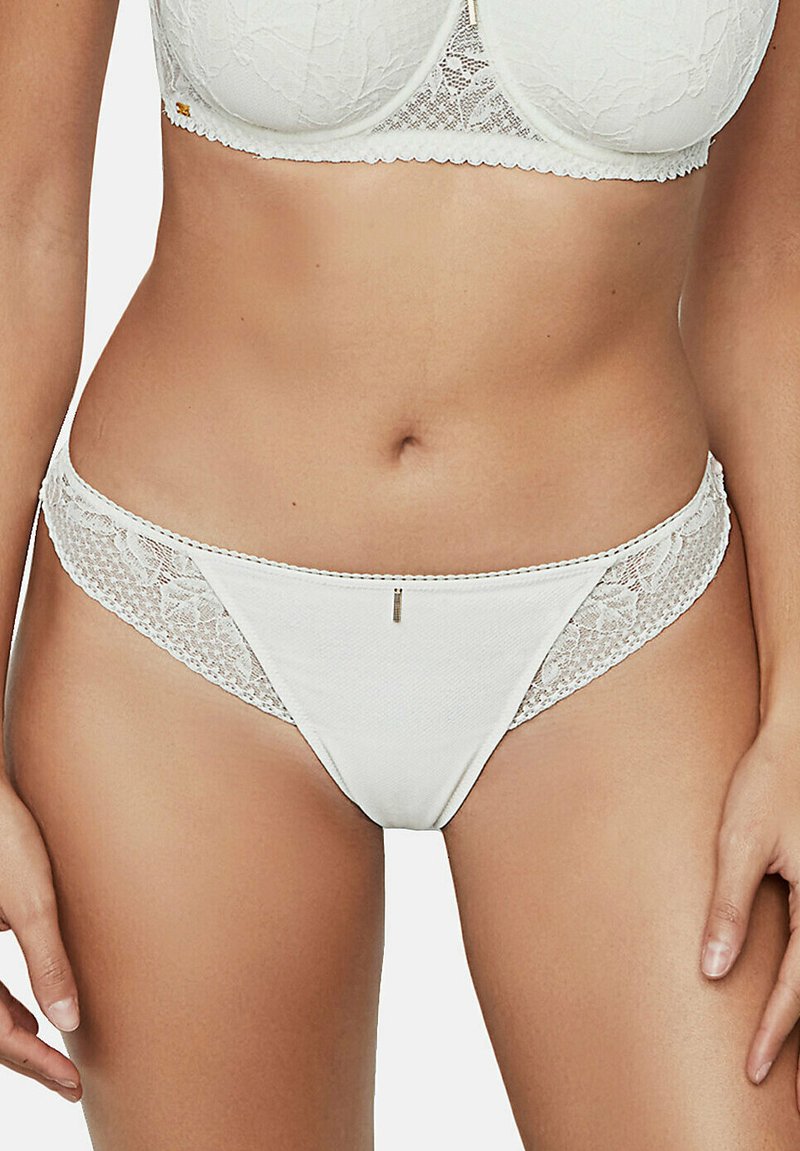 Witte slip met kant, met een gladde voorkant en delicate bloemkanten accenten aan de zijkanten, benadrukt door een klein metallic detail.