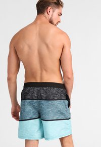 Plavky majú dizajn s farebným blokovaním v čiernej, šedej a tyrkysovej farbe. Elastický pás s vreckami, vyrobené z materiálu, ktorý rýchlo schne.