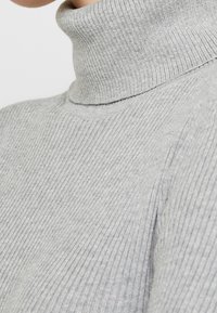 Gray ribbed turtleneck sweater with a fitted design, featuring a high collar and textured fabric. Focus on fine vertical lines and seamless edges.