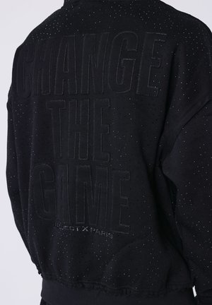 Felpa nera con sottili perforazioni e testo ricamato "CHANGE THE GAME" e più piccolo "PROJECT X PARIS" sul retro.