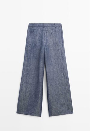 Pantaloni di jeans blu a gamba larga visti da dietro, con passanti per cintura e due tasche applicate posteriori.
