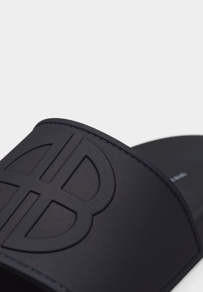 Fekete papucs nagy, egymásba fonódó "B" logóval a pánton, sima textúrával és látható varrási résszel.