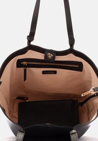 Czarna skórzana torebka z przestronnym beżowym wnętrzem, wyposażona w kieszeń zasuwaną na zamek, metkę z logo i złote akcenty.