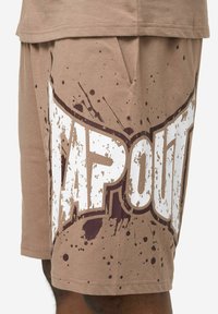 Smeđe kratke hlače od pamučne mješavine s velikim bijelim natpisom "TAPOUT" i smeđim prskalicama, širokog kroja s bočnim džepovima.