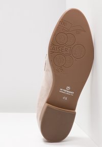 Bottine en suède beige avec un bout arrondi et lisse. La semelle présente un motif embouti décoratif. Nom de la marque : Peter Kaiser. Taille : 4½.