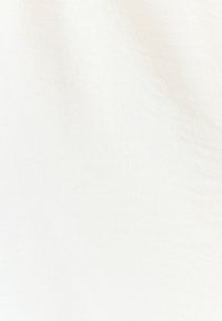 Weißer Stoff mit glatter Textur und subtilen Webmuster, der leichte Variationen in Farbton und Licht zeigt. Keine sichtbaren Muster oder Akzente.