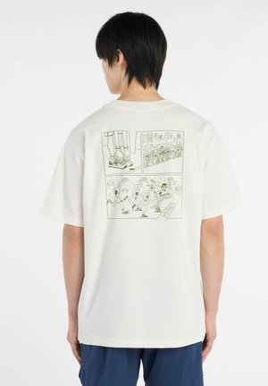 Persona che indossa una maglietta color avorio con un'illustrazione verde in stile fumetto di una corsa sulla schiena, con corridori e linea del traguardo.