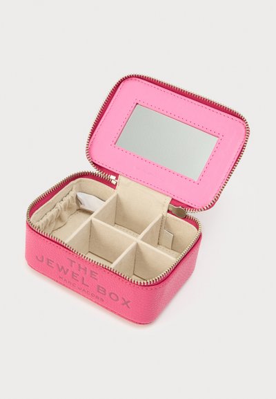 Ροζ δερμάτινο κουτί κοσμημάτων με φερμουάρ, διαθέτει καθρέφτη και πολλαπλές θήκες με επένδυση από μπεζ ύφασμα. Η επιγραφή «THE JEWEL BOX» τυπωμένη στο μπροστινό μέρος.