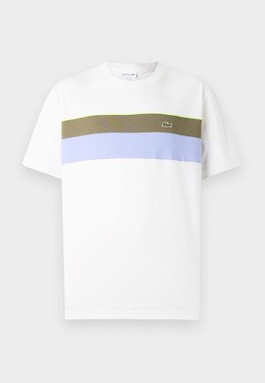 T-shirt bianca in cotone a maniche corte, con strisce orizzontali in verde oliva, azzurro chiaro e lavanda. Logo Lacoste sul lato sinistro del petto.