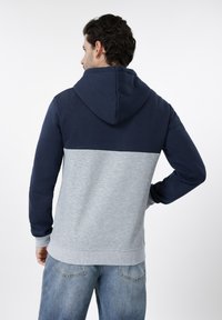 Φούτερ με κουκούλα που διαθέτει μπλε σκούρο επάνω τμήμα και ελαφρώς γκρι ριμπ κάτω μέρος, με ταιριαστά μανσέτες και υφή φινιρίσματος.