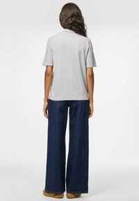 Pilka trumpa rankovė t-shirt su plačiomis mėlynomis džinsinėmis kelnėmis. Kelnės turi lygų paviršių ir subtilią siuvinėjimą, o t-shirt yra laisvo kirpimo.