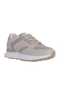 Zapatillas beige con laterales texturizados, parte superior de cuero liso y suela blanca. Incluyen cordones y un collar acolchado para mayor comodidad.