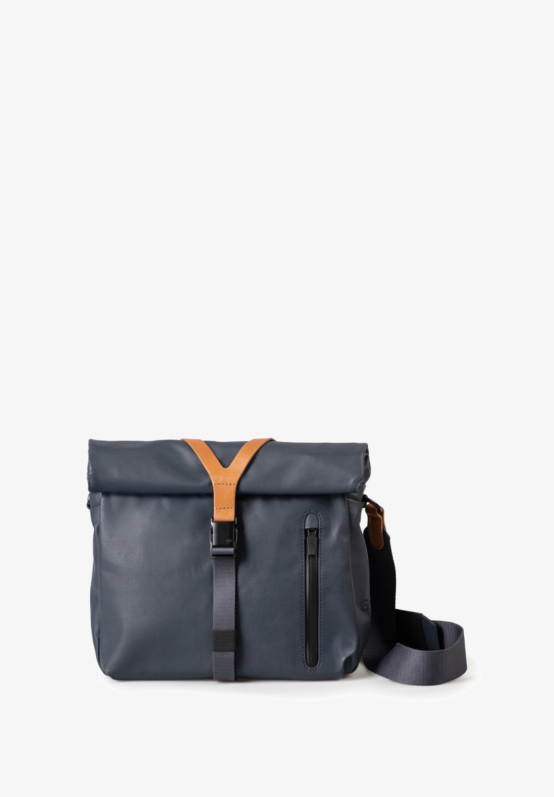 Navy waterproof bag with a roll-top closure, leather strap accents, and a front zip pocket. Features an adjustable shoulder strap.