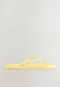 Gele teenslipper met een gestructureerde zool en dunne banden, ontworpen in een eenvoudige, minimalistische stijl met een vlakke, flexibele constructie.