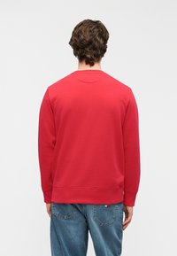 Sweatshirt rouge à col rond en tissu de coton doux, avec des poignets et un ourlet côtelés. Vue de dos montrant une texture lisse et un design simple.