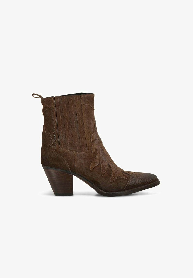 Stivale alla caviglia in suede marrone con punta affusolata e tacco impilato. Caratterizzato da pieghe verticali e motivi decorativi intagliati sui lati.