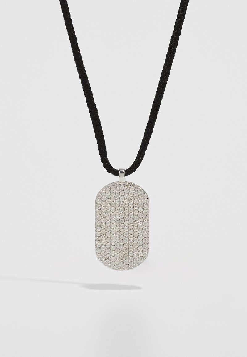 Pendente d'argento dalla forma rettangolare, con una superficie testurizzata arricchita da piccole pietre rotonde e scintillanti, appeso a una corda intrecciata nera.