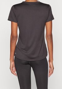 Černé sportovní tričko s krátkým rukávem, kulatým límcem a hladkým povrchem. Má mírný ležérní vzhled a minimalistic design bez vzorů.