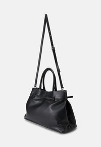 Zwarte leren tote bag met een zachte textuur, dubbele handgrepen aan de bovenkant en een afneembare schouderband. Beschikt over subtiele stiksels en een ontspannen vorm.