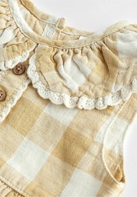 Leinenkleid mit gelben und weißen Karos, gerafftem Ausschnitt, cremiger Häkelkante und Holzknöpfen, mit einem lockeren Schnitt.
