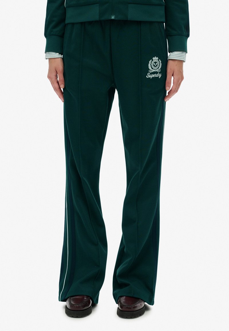 Grønne fleece joggingbukser med præget logo, stribede detaljer og sidelister; løs pasform med vide ben og en glat overflade.