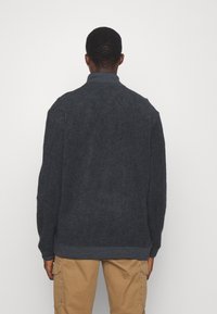 Dunkelgraue Fleecejacke mit hohem Kragen, gerippten Bündchen und Saum; verfügt über eine strukturierte Oberfläche und ein lässiges Design.