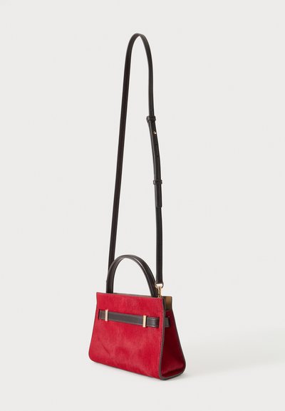 Petit sac à main rouge avec poignée courte noire, longue bandoulière noire réglable et détails en métal doré.