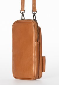 Taschenüberschlag aus hellbraunem Leder mit glatter Textur, rechteckiger Form, einem Reißverschluss oben und einem Markenetikett an der Seite.