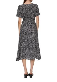 Robe midi noire à fleurs avec de courtes manches bouffantes, taille cintrée et jupe fluide ornée de petits motifs de fleurs blanches et roses.