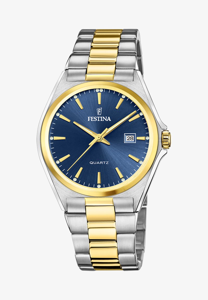 Sudraba un zelta metāla pulkstenis ar zilu ciparnīcu, dzelteniem stundu marķieriem, datuma rādītāju 3. stundā un struktūru. Kvarca kustība.