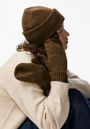 Brown wool beanie with ribbed cuff and matching brown mittens with a textured finish. Soft, cozy fabric paired with a light beige sweater.