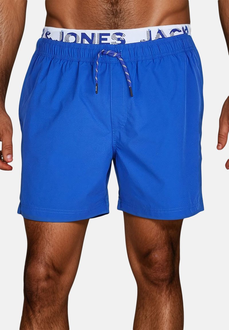 Shorts de bain bleus en tissu léger, dotés d'une taille élastique avec un logo blanc et un cordon de serrage.