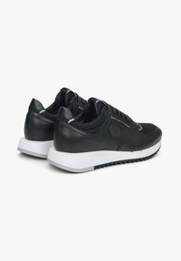 Czarne buty sportowe z połączeniem skóry i materiału siateczkowego, okrągłym noskiem i białą gumową podeszwą z teksturowym gripem.
