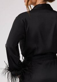 Czarna satynowa szlafrok z długimi rękawami, które mają czarne pióra na mankietach, oraz pasującym paskiem. Gładka tekstura z klasycznym wzorem.