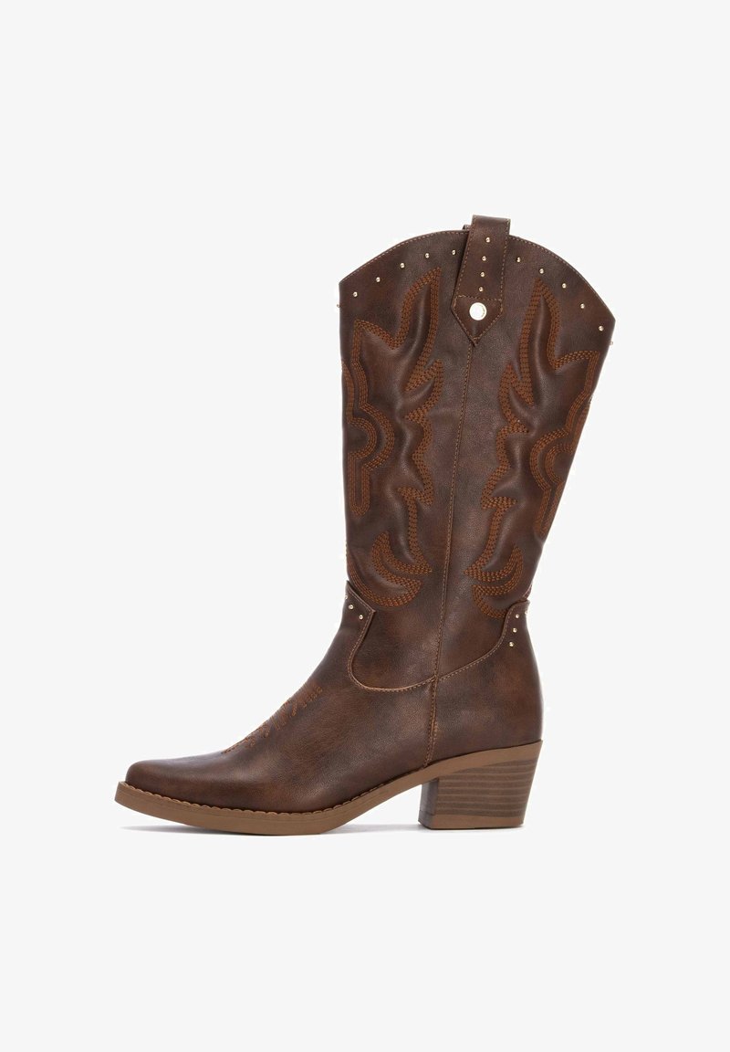 Bota de vaquero de cuero marrón con punta afilada, costuras decorativas, patrones en relieve y pequeños remaches en el caña y el tacón.