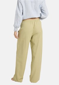 Pantalon large rayé vert clair avec une taille élastique, associé à une chemise boutonnée à rayures bleues et blanches.