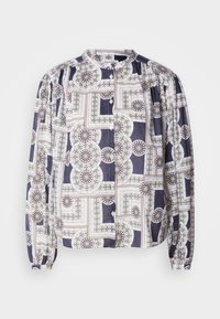 Blusa a fantasia con scollo rotondo, maniche lunghe a palloncino, chiusura con bottoni, caratterizzata da motivi geometrici nei colori blu navy, bianco e verde.