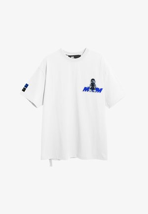 Camiseta blanca oversize con un pequeño personaje de dibujos animados y texto azul "MOD" en el pecho, y diseño a rayas azul-negro en la manga izquierda.