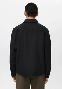 Black jacket with a collared neckline, long sleeves, and buttoned cuffs. Smooth texture, minimal design with no visible patterns.