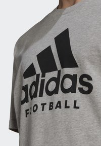T-shirt grigio in cotone con il testo nero "adidas" e "FOOTBALL", completo dell'iconico logo delle tre strisce sul lato superiore sinistro.