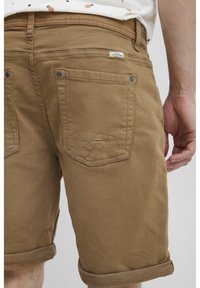 Braune Baumwollshorts mit umgeschlagenen Säumen, ausgestattet mit zwei Gesäßtaschen mit eingeprägtem Stitching. Etikett in den Taillenbund genäht.