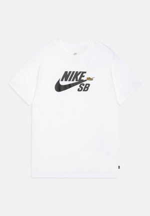 Camiseta blanca de manga corta de Nike SB con logo y símbolo swoosh negros, y un pequeño gráfico de una zapatilla amarilla en el pecho.