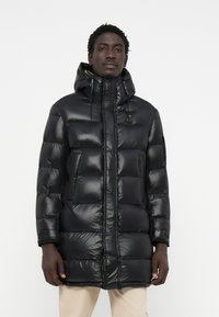 Black puffer coat with a shiny finish, featuring a hood, zip closure, and side pockets. The design includes a quilted texture.