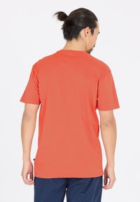 Kortärmad T-shirt med rund halsringning i klar orange, tillverkad av ett mjukt tyg. Har en avslappnad passform utan synliga logotyper eller mönster.