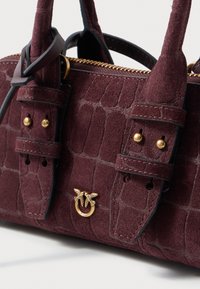Borsa a tracolla in suede bordeaux con motivo coccodrillo, dotata di accessori in oro, chiusura con zip e doppio manico corto con accentuazioni decorative.