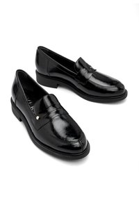 Black leather loafers with a shiny finish, featuring a decorative strap and a small metallic accent. Low heel and cushioned insole.