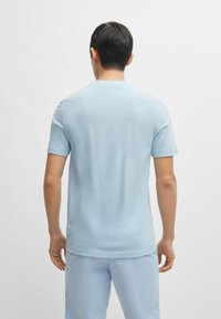 Light blue short-sleeve t-shirt with a smooth texture and crew neck, paired with light blue shorts, viewed from the back.